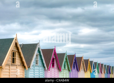 Eine Reihe von bunten Strandhäuschen unter Gewitterhimmel Stockfoto