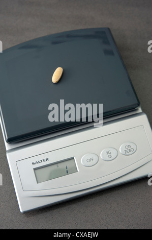 Waage mit einem Gewicht von einem Gramm Vitamin-Pille. Stockfoto