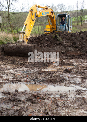 Auftragnehmer mit einem 360-Grad-Bagger graben Teich Tiere auf einem Bauernhof. Powys, Wales. April Stockfoto