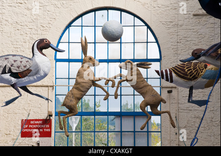 Kunstinstallation von Federwild und springenden Hasen hängen vom Dach der Markthalle in Abergavenny Food Festival Stockfoto