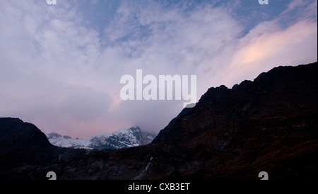 Wolken treiben über der Oberseite eines Berges in der Abenddämmerung in Langtang Nationalpark, Nepal Stockfoto