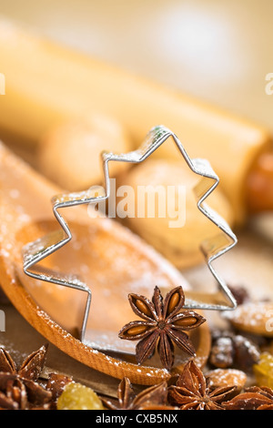 Weihnachten backen. Baum geformt Ausstecher mit Sternanis auf Holzlöffel umgeben von Rosinen, Mandeln und Nüssen Stockfoto