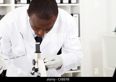 afroamerikanische männliche Labor Forscher auf der Suche durch Mikroskop Stockfoto