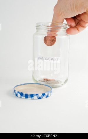 Eine Hand, ein Glas des Geldes mit Studiengebühren Gebühren Label hinzufügen. Stockfoto