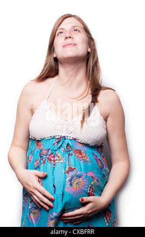 Eine attraktive junge Frau steht, ihren Bauch halten und Lächeln. Stockfoto