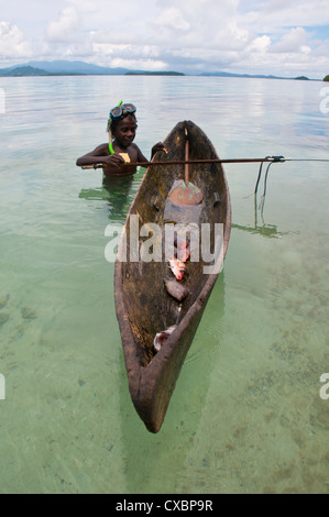 Kleiner Junge geht mit seinem Kanu und Harpune, Marovo Lagune, Salomonen, Pazifik Fischen. Stockfoto