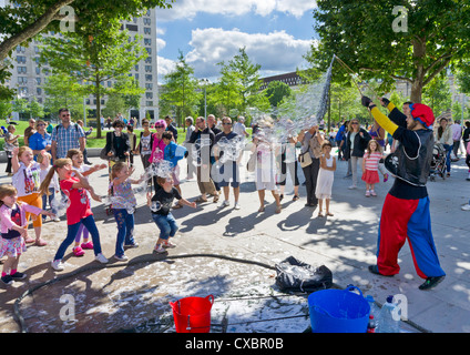 Kinder und Eltern beobachten einen Streetart-Künstler machen riesige Seifenblasen Jubilee Gardens London England UK GB EU Mitteleuropa Stockfoto