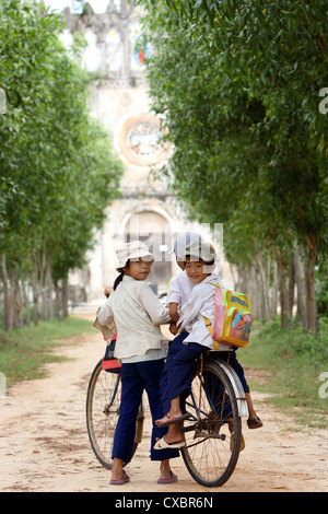 Vietnam, vietnamesische Kinder auf einem Fahrrad, umgeben von Bäumen gesäumten Allee, Hue Stockfoto