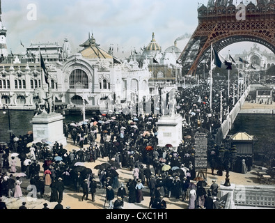 Farbenprächiertes Hochwinkelbild vom Trocadero aus mit einer Menge Ausstellungsbesuchern auf der Pont d’Iena, unter dem Eiffelturm und entlang des Champ de Mars auf der Pariser Ausstellung von 1900, auch bekannt als Exposition Universelle von 1900, Paris, Frankreich, 1900. Der Palais de l'Electricite und das Chateau d'Eau sind am Ende des Champ de Mars zu sehen. Der Palais de la Navigation de Commerce befindet sich links von der Pont d’Iena am Ufer der seine. (Foto von Burton Holmes) Stockfoto