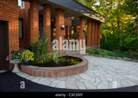 Vor dem Eingang mit Teich und Stein Veranda auf rote Backsteinhaus mit Säulen am Sonnenuntergang Toronto Ontario Kanada Stockfoto