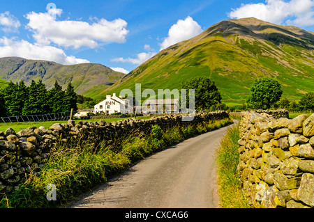 Eine schmale Gasse, gesäumt von Trockenmauern Wände Winde auf dem Wasdale Head Inn eingebettet in tiefste Tal am Fuße des majestätischen Gipfeln Stockfoto