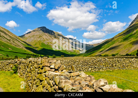 Majestätische schroffe Gipfel ragen über friedlichen grünen Wiesen umgeben von Trockensteinmauern an der Spitze der tiefste Tal, Lake District Stockfoto