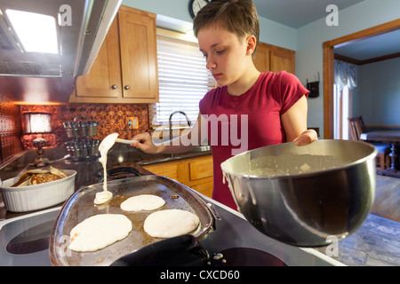 Weibliche Teenager Pfannkuchen zum Frühstück in ihrer Küche zubereiten. Stockfoto