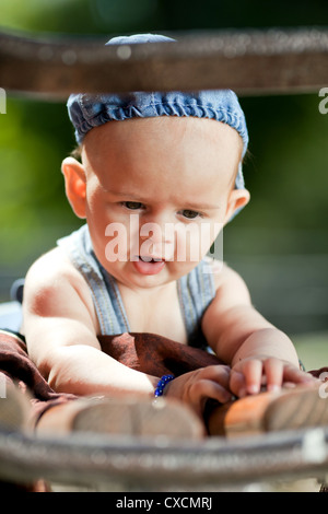 Sechste Reittiere alten Babyjungen spielen auf einer Holzbank Stockfoto