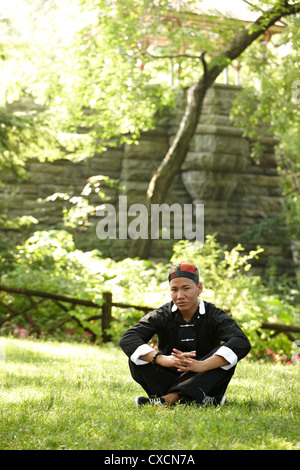 Mann in der traditionellen asiatischen Kleidung sitzen in Rasen Stockfoto