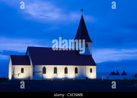 Vik (Vik ich Myrdal) Kirche in der Morgendämmerung mit Reynisdrangar (Basalt-Meer-Stacks) im Hintergrund, Südisland Stockfoto