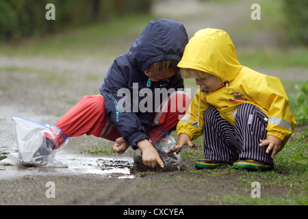 Berliner Kinder spielen im regen Getriebe in einer Pfütze Stockfoto