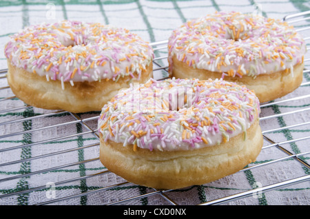 Donuts mit Puderzucker und bunte Streusel auf einen Backrost Stockfoto