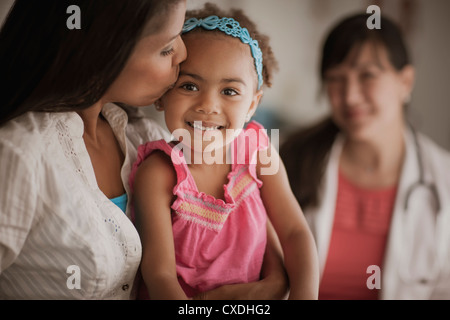 Mutter küssen Tochter in Arztpraxis Stockfoto