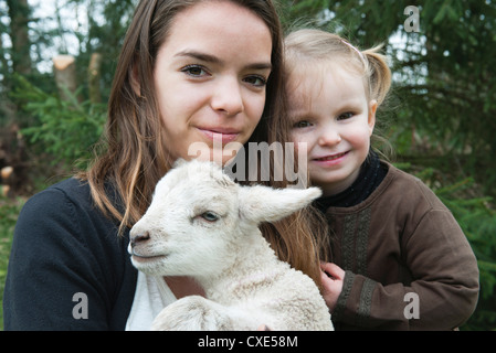 Teenager-Mädchen und kleine Schwester mit Haustier Lamm, Porträt Stockfoto