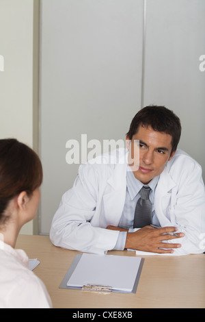 Arzt gegenüber Patientin sitzt Stockfoto