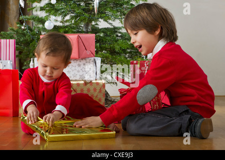 Präsentiert von jungen helfen, seine kleine Schwester Weihnachten öffnen Stockfoto