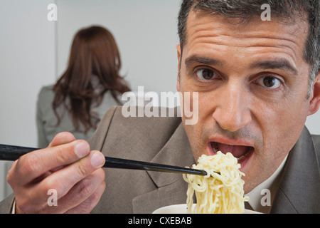 Reife Geschäftsmann Essen Ramen-Nudeln im Büro Stockfoto