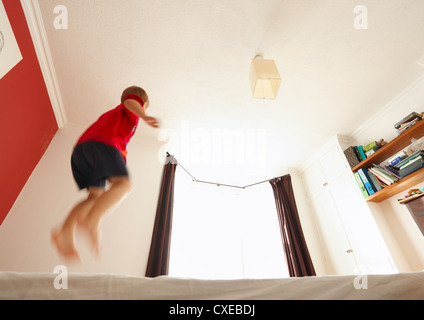 Vier Jahre alter Junge auf dem Bett hüpfen. Stockfoto