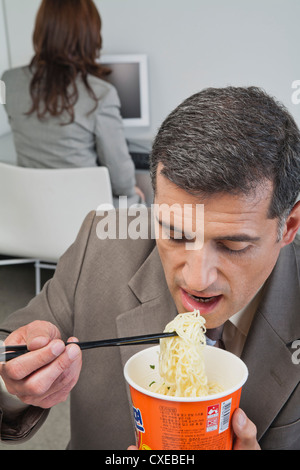 Kaufmann Essen Ramen-Nudeln im Büro Stockfoto