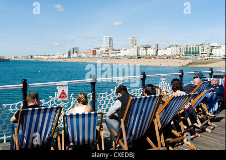 Leute sitzen in Liegestühlen am Pier von Brighton Stockfoto