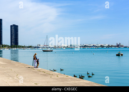 Schwangere junge Mutter mit kleinen Jungen füttern die Enten am See im Grant Park, Chicago, Illinois, USA Stockfoto