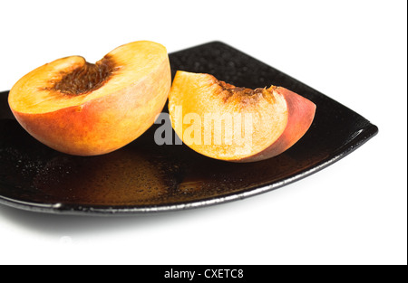 rote Pfirsiche Scheiben auf schwarzem Teller Stockfoto