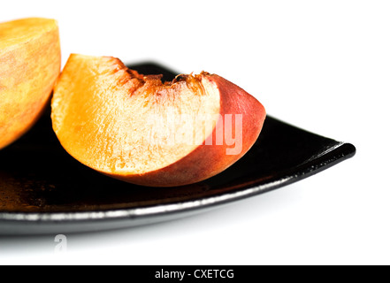 rote Pfirsiche Scheiben auf schwarzem Teller Stockfoto