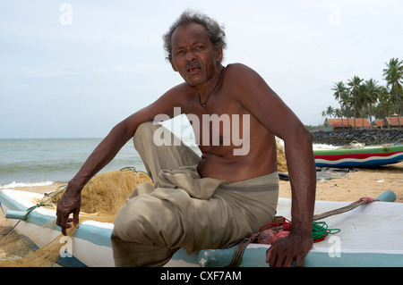 Ältere Fischer sitzt auf dem Rand von seinem Fischerboot, Waikkal Dorf, Sri Lanka Stockfoto