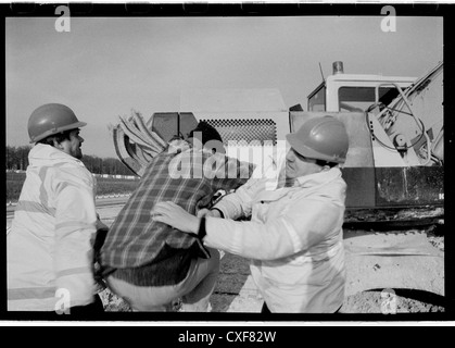 Gruppe 4 Sicherheit versucht, ein Demonstrant daran zu hindern, Erdbewegungsmaschinen. M3-Erweiterung Winchester. Stockfoto