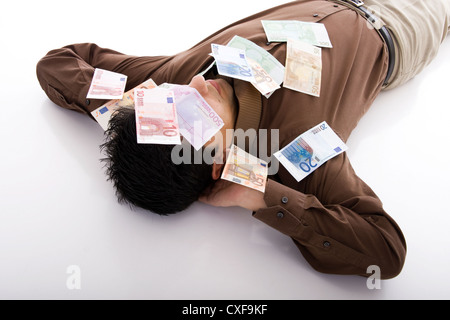 Business-Mann schlafen mit vielen Euro-Banknoten Stockfoto