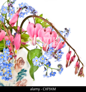 Ein Bouquet von Blutungen Herzen und vergiß mich Habenichtse in einer kleinen Töpferei Vase. Stockfoto
