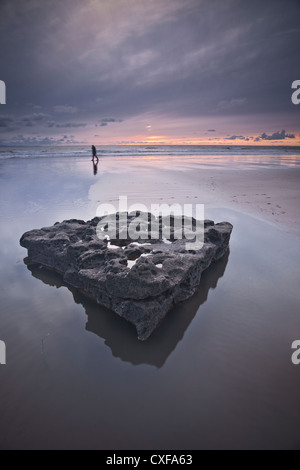 Ein einsamer Dogwalker schlendert über den Strand von Dunraven Bay in der Nähe von Southerndown an der Küste von Glamorgan Heritage. Stockfoto