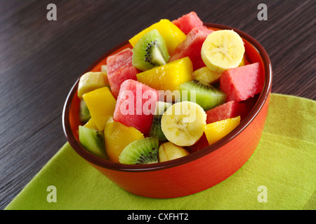 Salat von frischen Früchten hergestellt, Banane, Kiwi, Wassermelone und Mango Stücke in orange Schüssel Stockfoto
