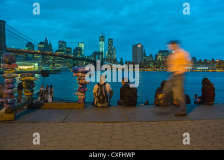 New York City, NY, USA, Touristen sitzen anschauen Skyline von Manhattan in der Dämmerung von DUMBO Brooklyn Bridge Park Stockfoto