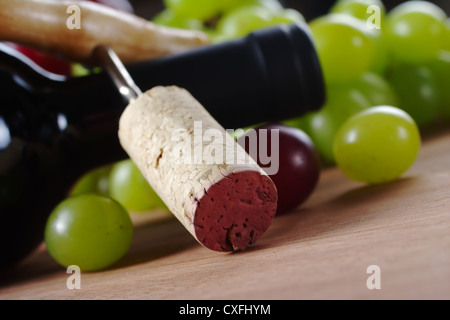 Kork auf Korkenzieher gelehnt eine Flasche Wein umgeben von Trauben Stockfoto