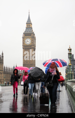 Menschen zu Fuß über Westminster Brücke im Regen mit Big Ben im Hintergrund Stockfoto