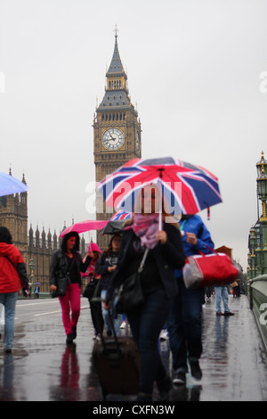 Menschen zu Fuß über Westminster Brücke im Regen mit Big Ben im Hintergrund Stockfoto