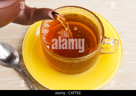 Tee in Tasse auf Untertasse gegossen wird Stockfoto