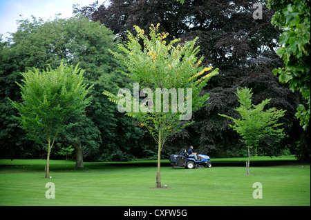 Ein Gärtner mäht den Rasen mit einem Sit am Mäher auf dem Rasen Nuffield Worcester College in Oxford Stockfoto