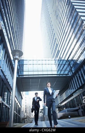 Eine Business-Frau und ein Business-Mann läuft zwischen Bürogebäuden Stockfoto