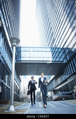 Eine Business-Frau und ein Business-Mann läuft zwischen Bürogebäuden Stockfoto