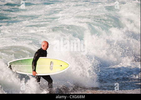 Ein Surfer, ein Spaziergang durch Seegang bei Sennen in Cornwall Stockfoto