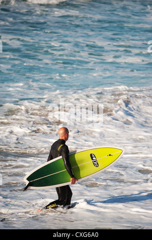Ein Surfer, ein Spaziergang durch die Brandung bei Sennen in Cornwall Stockfoto