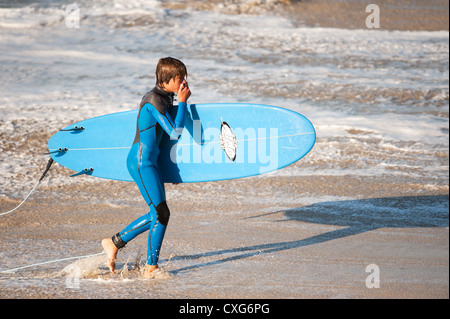 Ein junger Surfer zu Fuß aus dem Meer bei Sennen in Cornwall Stockfoto